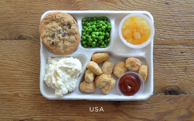 Nos Estados Unidos, o cardápio fica assim: pedaços de frango frito com catchup, purê de batata, ervilhas, frutas em pedaços e biscoito com gotas de chocolate